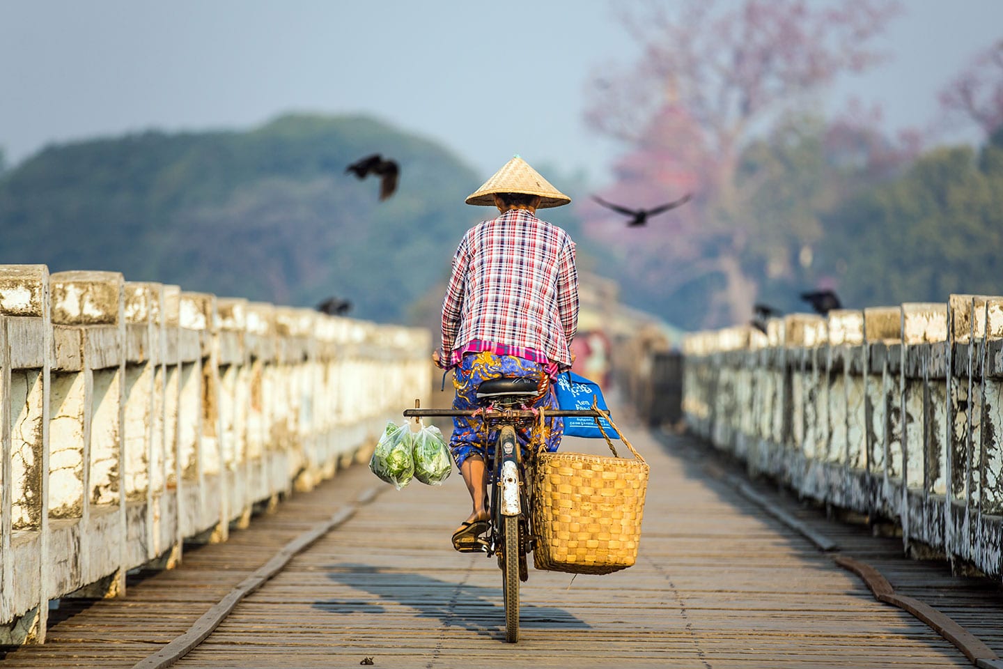 Old man biking over a wooden bridge in Myanmar