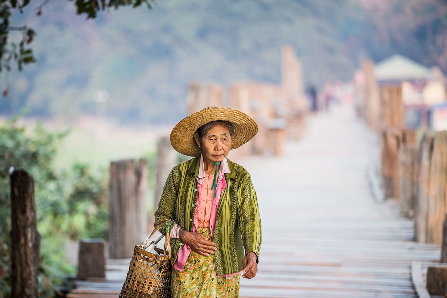 Old woman walking on a wooden bridge in Myanmar