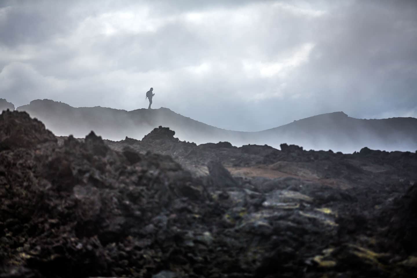 Tourist walking on a volcanic lava field in Krafla, Iceland