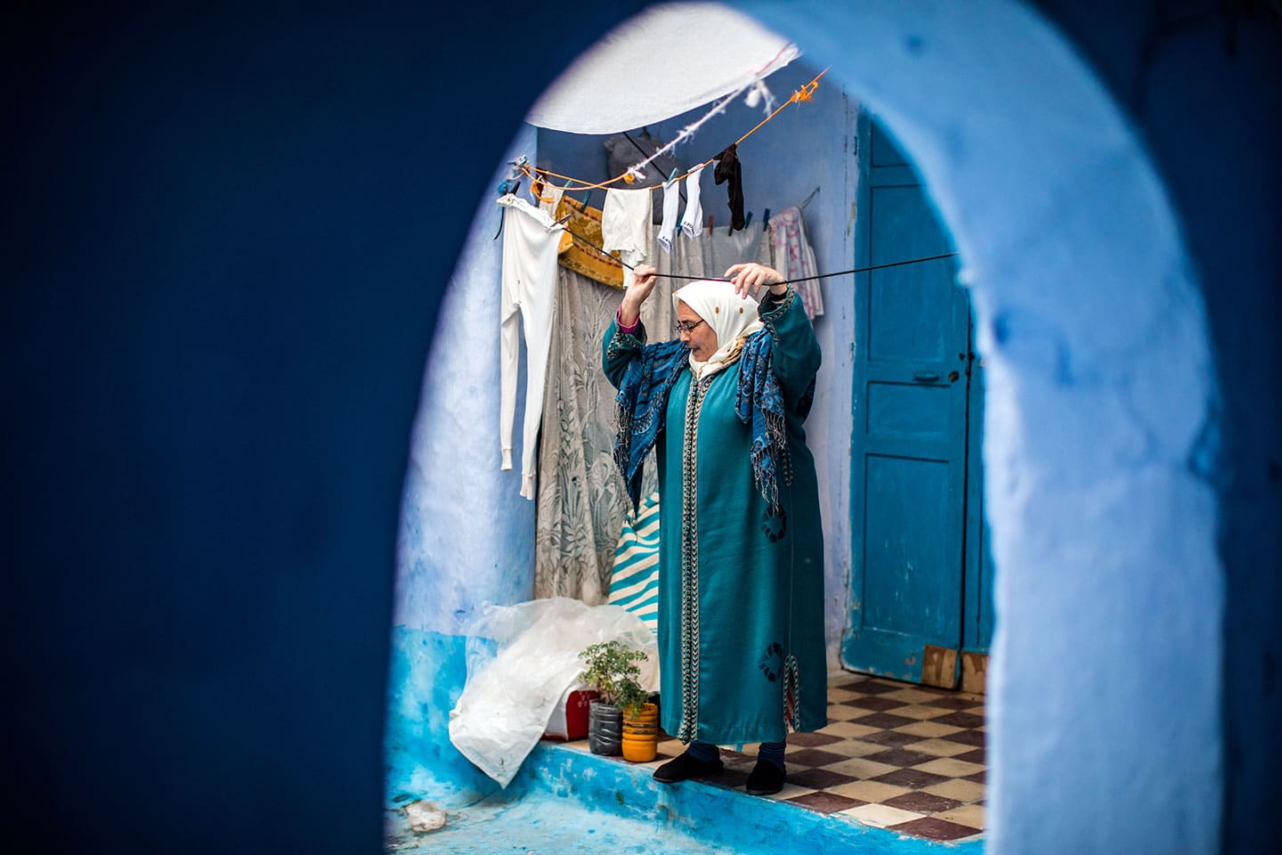 Woman hanging her laundry in the blue town of Chefchaouen, Morocco